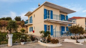 Un bâtiment à deux étages, doté d’un toit plat, de volets bleus et d’un balcon.