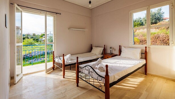 Une chambre avec deux lits, un balcon et une fenêtre.