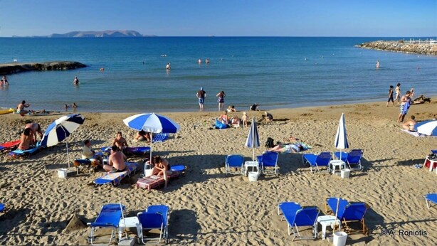 A beach with blue and white umbrellas, sun loungers, and people swimming in the water. - Cretan Magnolia Gem - Smari Cozy Getaway (Minoa Pediada)