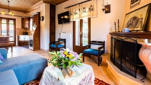 A cozy living room with a fireplace, a television, and a dining area with wooden cabinets.