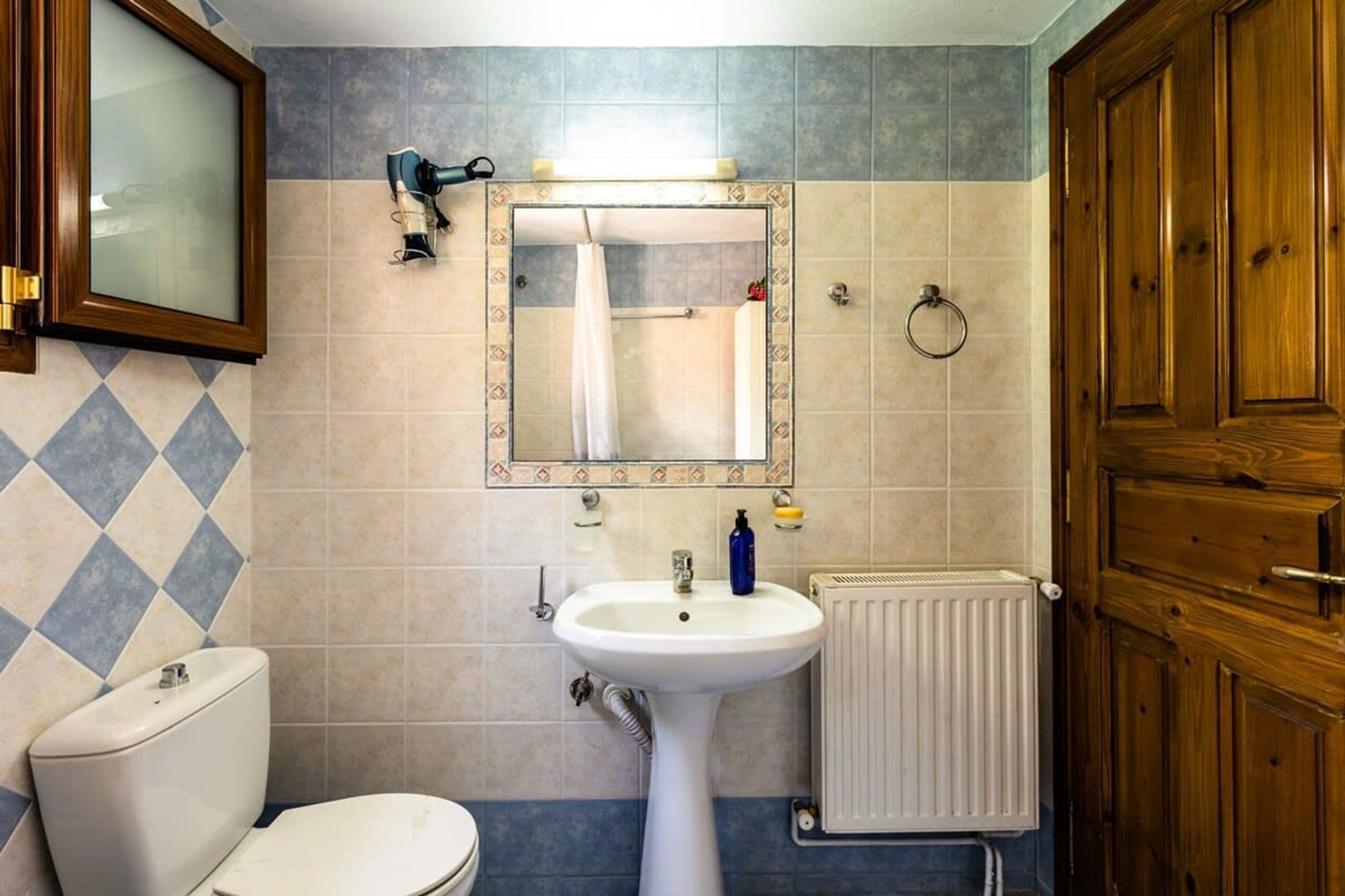 Een badkamer met een wit wastafel, een spiegel, een douche en een toilet.