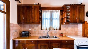 A kitchen with wooden cabinets, a sink, a stove, and a window with a curtain.