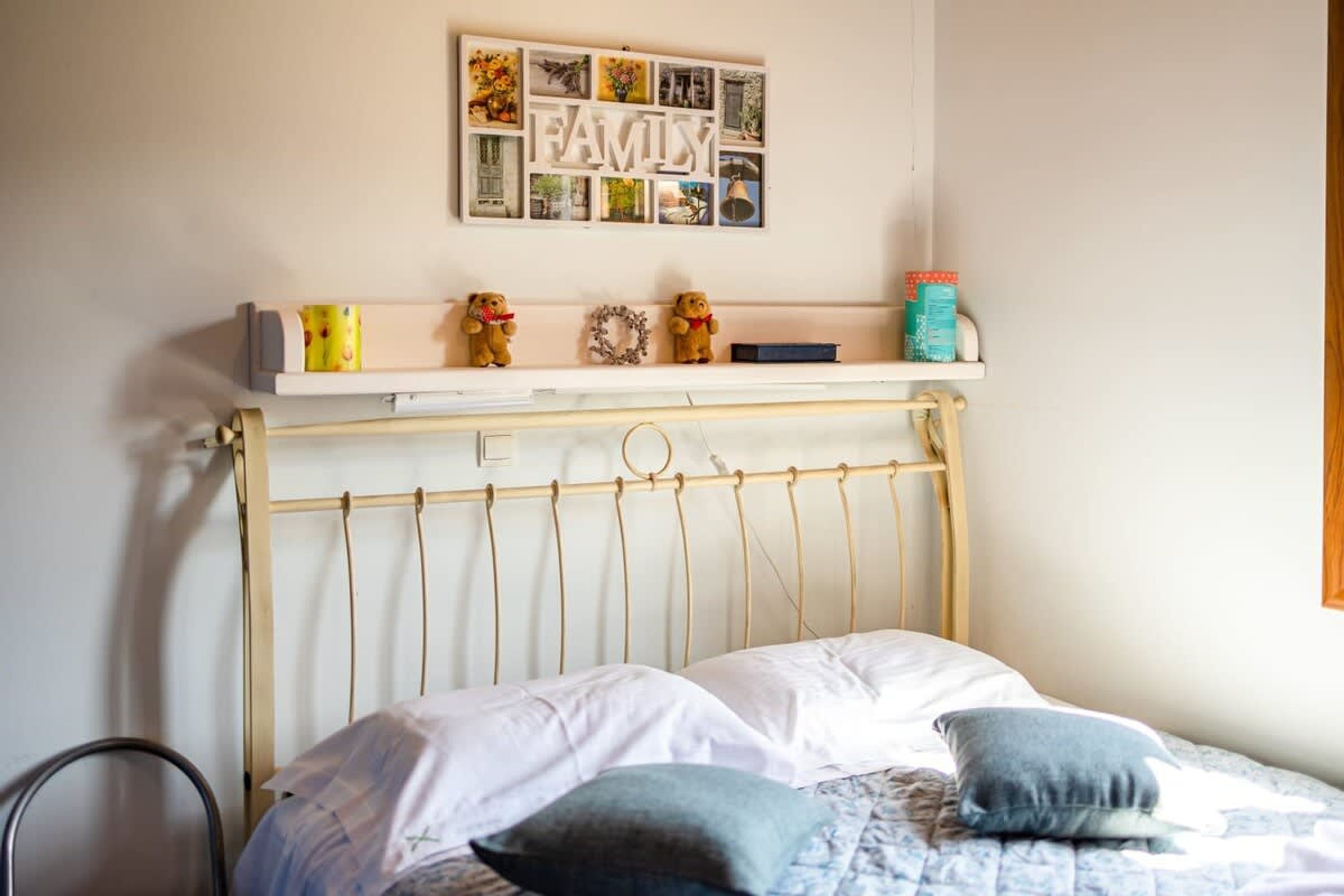 Ein Schlafzimmer mit Bett, Kissen, einem Regal mit Dekoration und einem an der Wand befestigten Bilderrahmen.