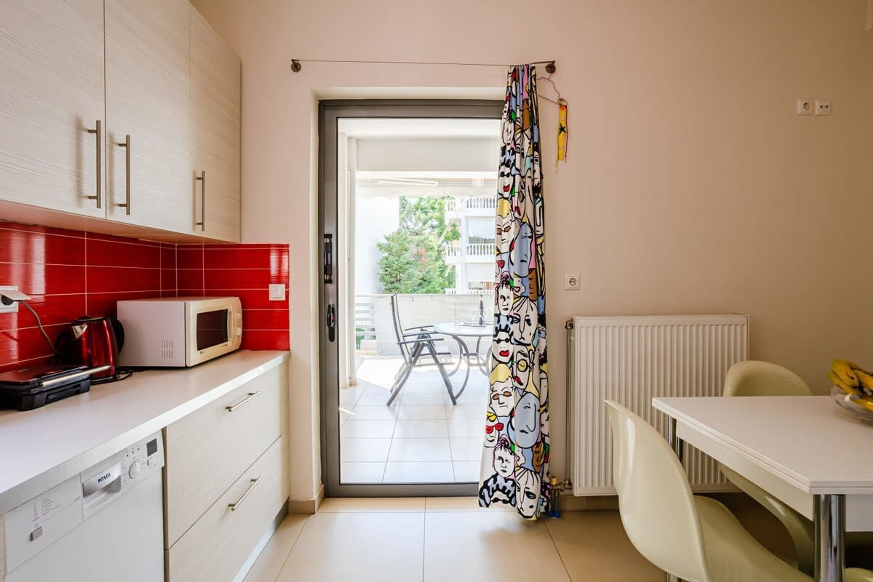 A compact kitchen with a microwave, a kettle, and a dining area with a table and chairs.