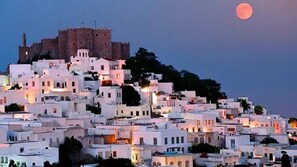 A town with white buildings and a castle on a hill, under a moonlit sky. - Anoi Traditional House Patmos Architectural Charm (Patmos)