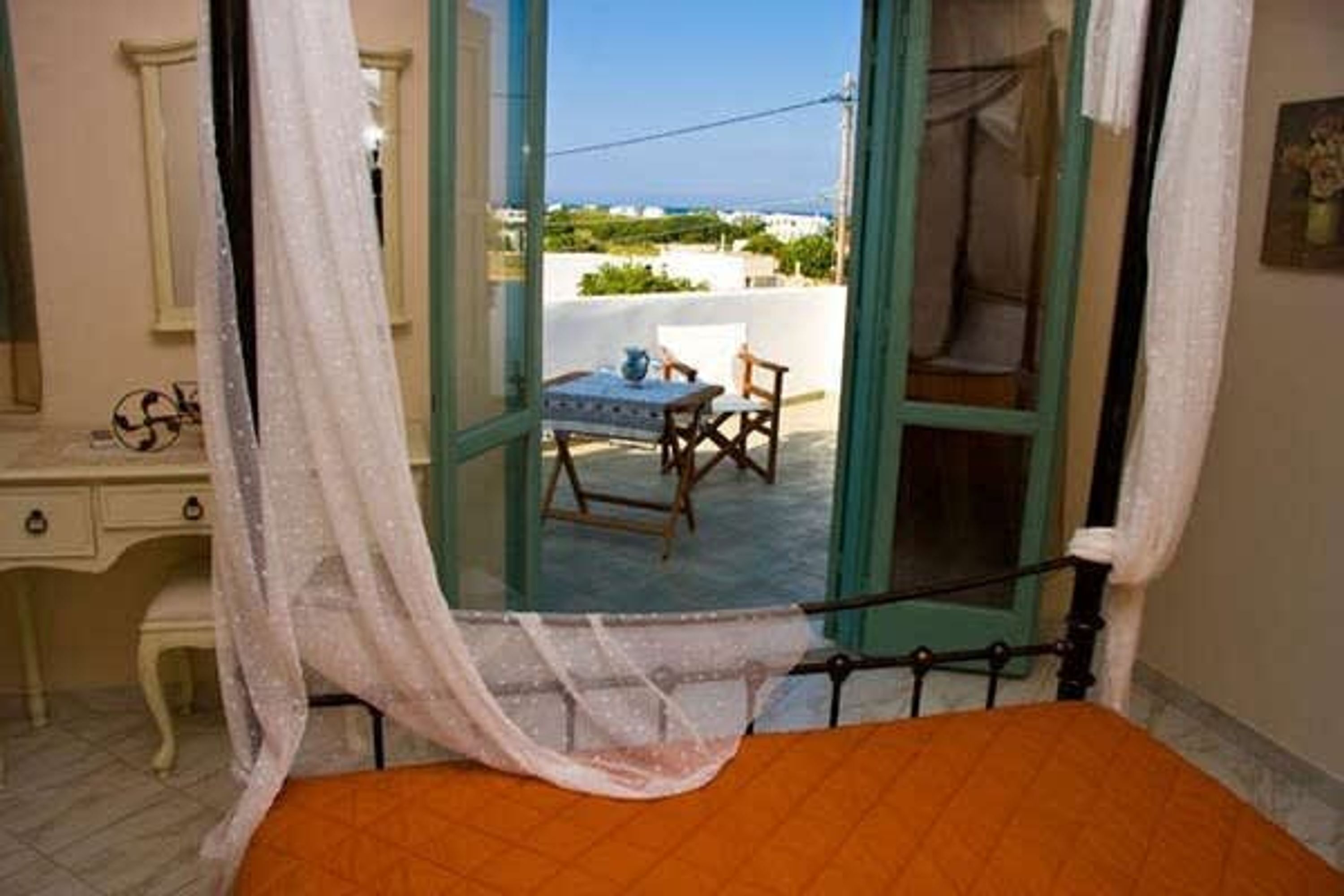 Ein Schlafzimmer mit Bett, Nachttisch, Stuhl und Blick auf den Balkon.