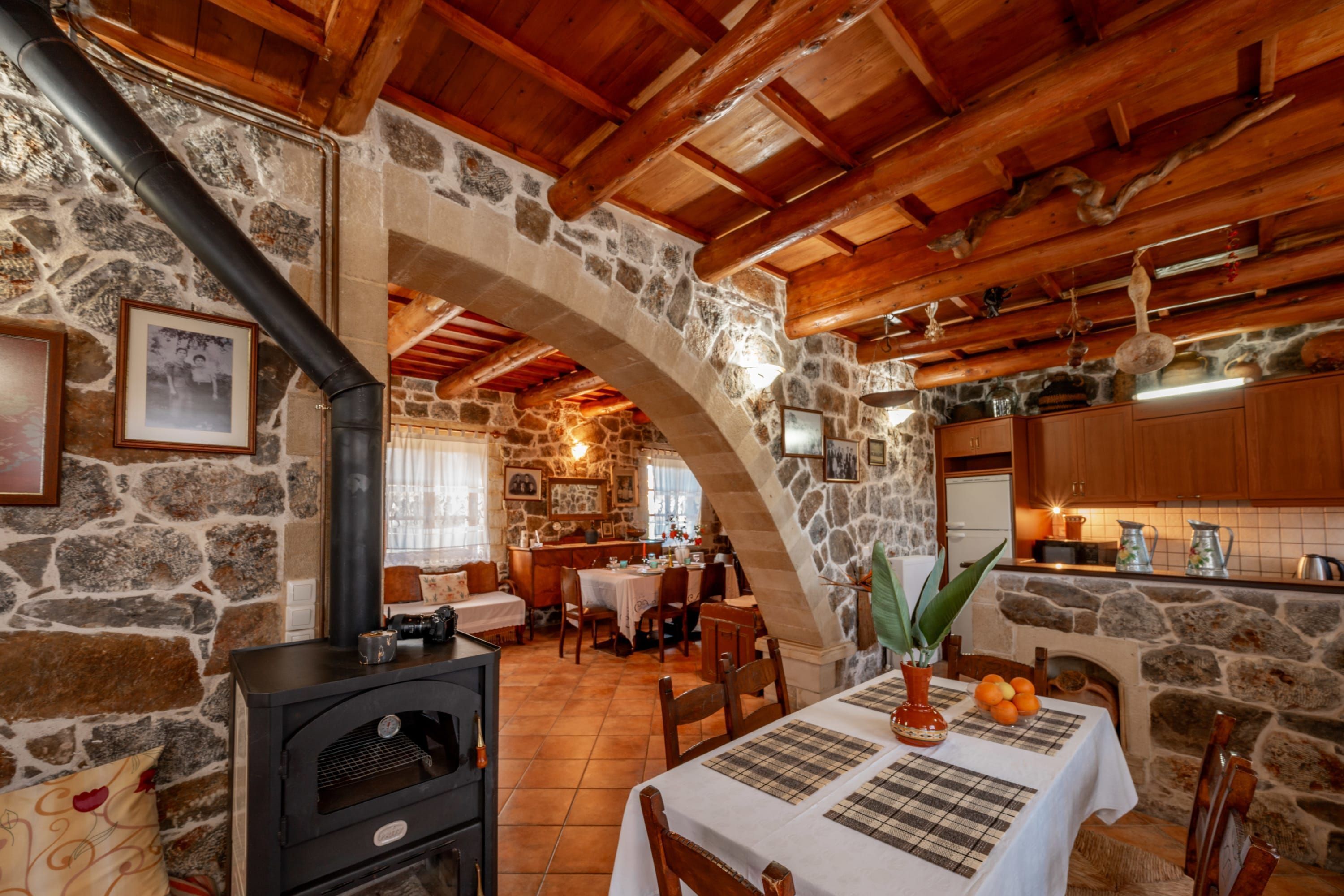 Interior rústico de piedra con chimenea de piedra, vigas de madera y comedor con mesa dispuesta para dos.