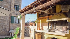 A rustic outdoor kitchen with a brick oven, wooden counter, and hanging baskets. - Maria s Serene Countryside Retreat by Chania (Chania)