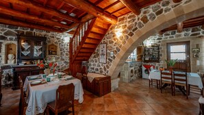 A rustic dining area with stone walls, wooden beams, and a high ceiling. - Maria s Serene Countryside Retreat by Chania (Chania)