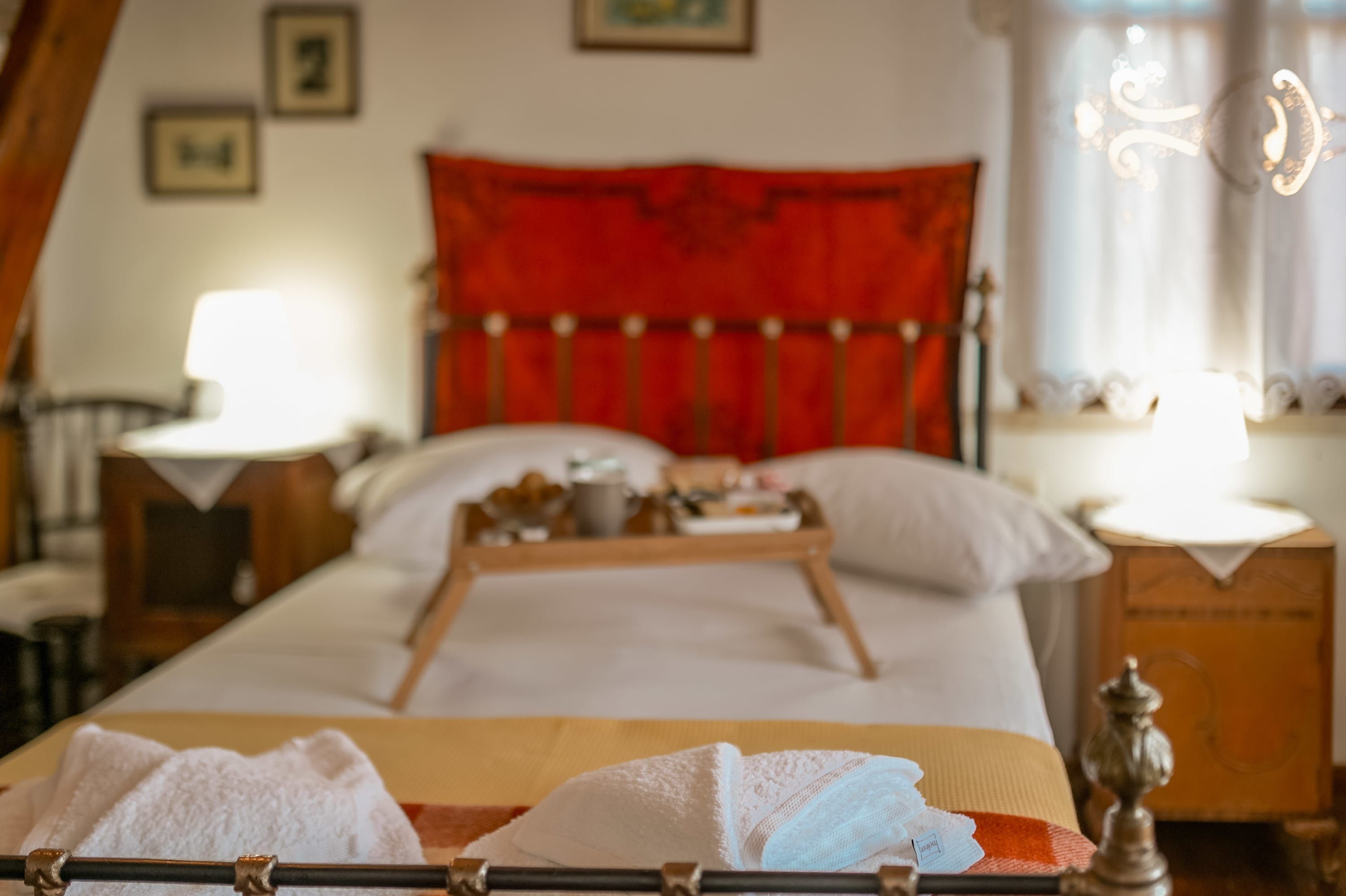 Una habitación de hotel con una cama, una bandeja de desayuno, una lámpara y una mesita de noche.