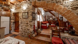 Un'accogliente stanza in pietra con cucina, zona pranzo e una scala che conduce a una mansarda.
