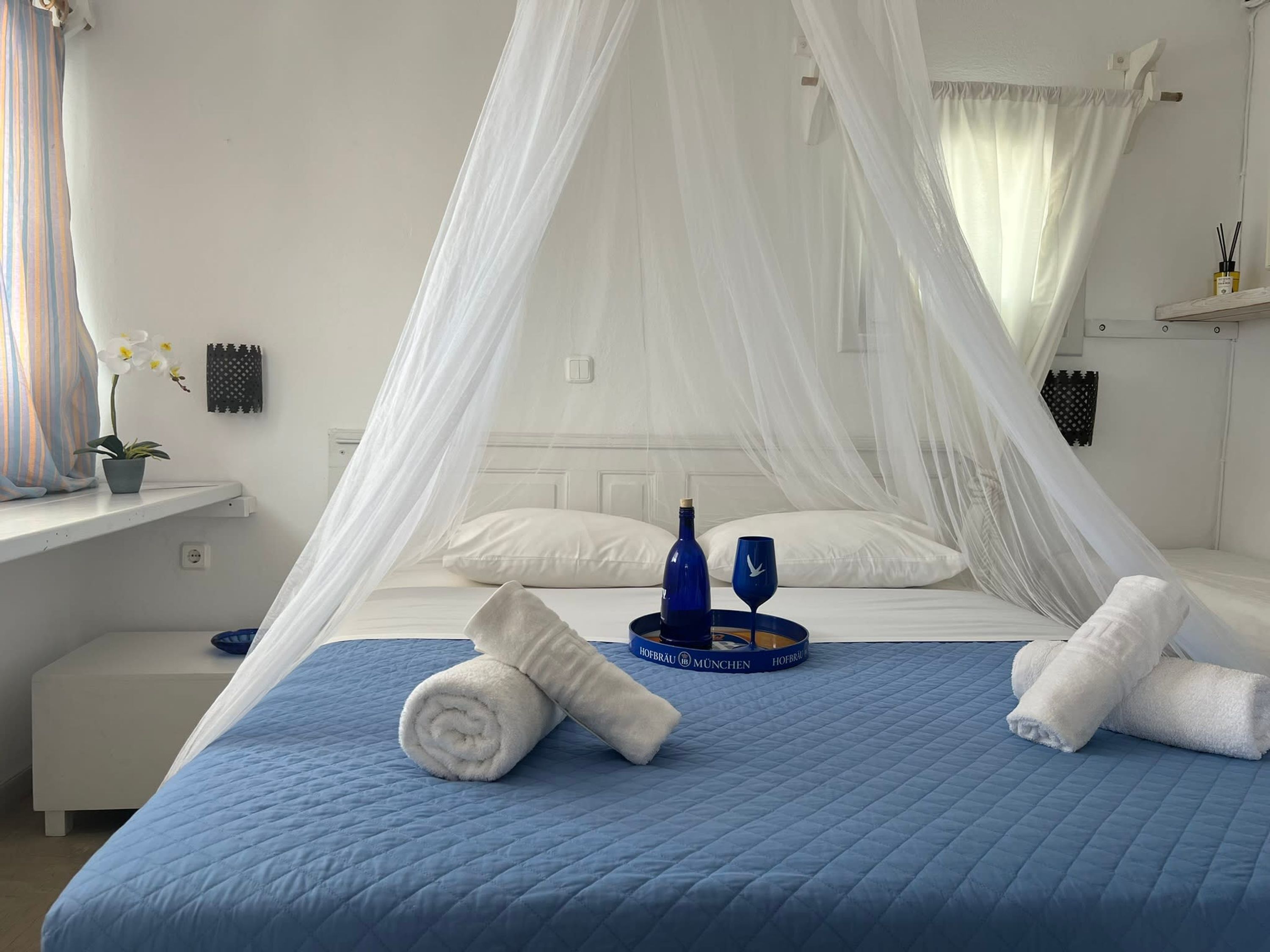 Un lit bien fait, avec une couette bleue, des oreillers blancs et un ciel de lit blanc.