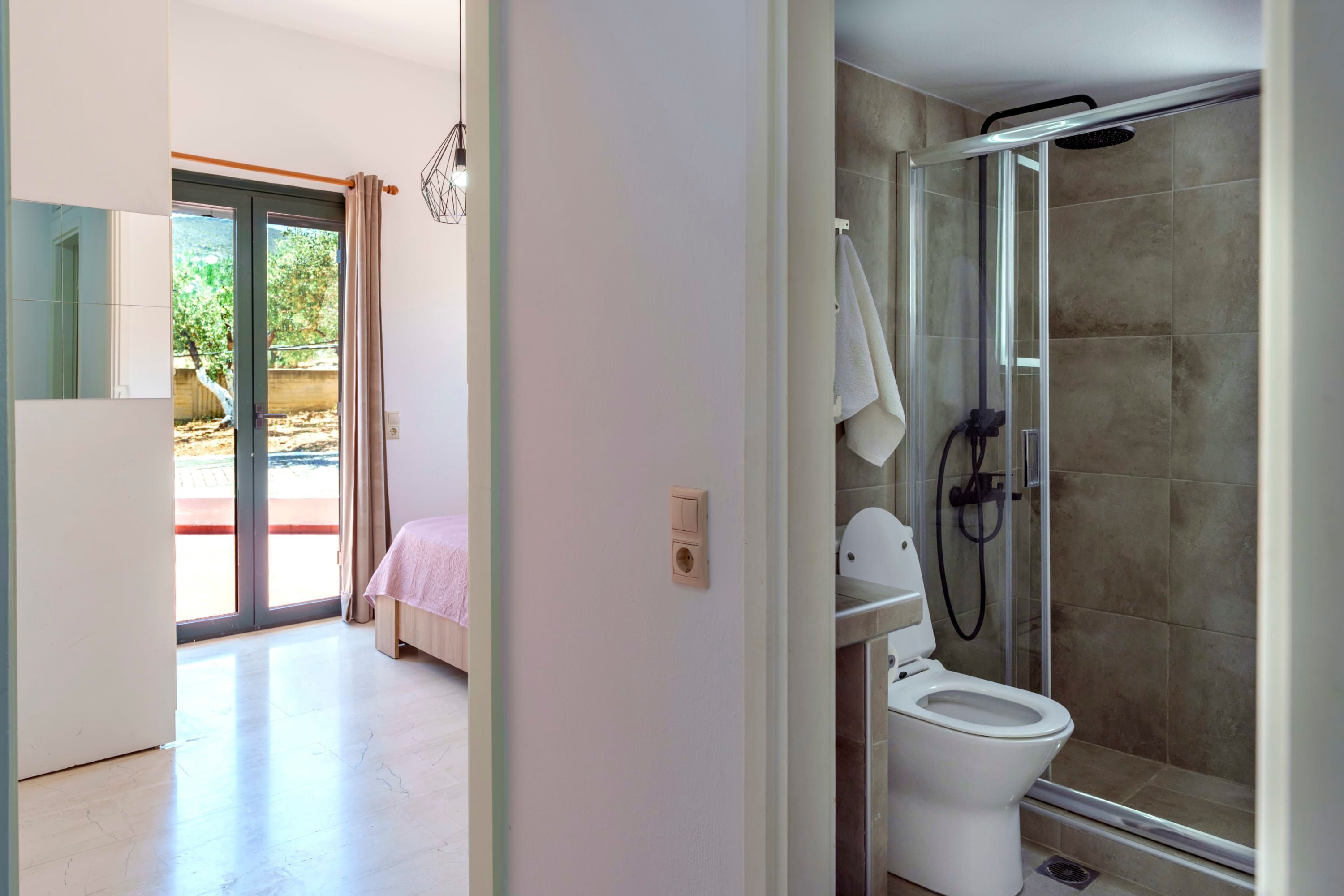 A modern bathroom with a glass shower enclosure, a toilet, and a visible towel rack.