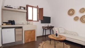 A compact living space with a kitchenette, a sofa, a coffee table, and a TV. - Santorini Rooftop Hot Tub Suite w Panoramic Views (Santorini)