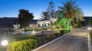 A modern hotel with a paved driveway, well-maintained gardens, and a clear view of the surrounding landscape.