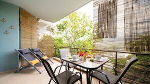 A balcony with a table set for dining, chairs, and a sun lounger. - Urban Bloom Oasis - Mini Zen Maison (Kalamata)