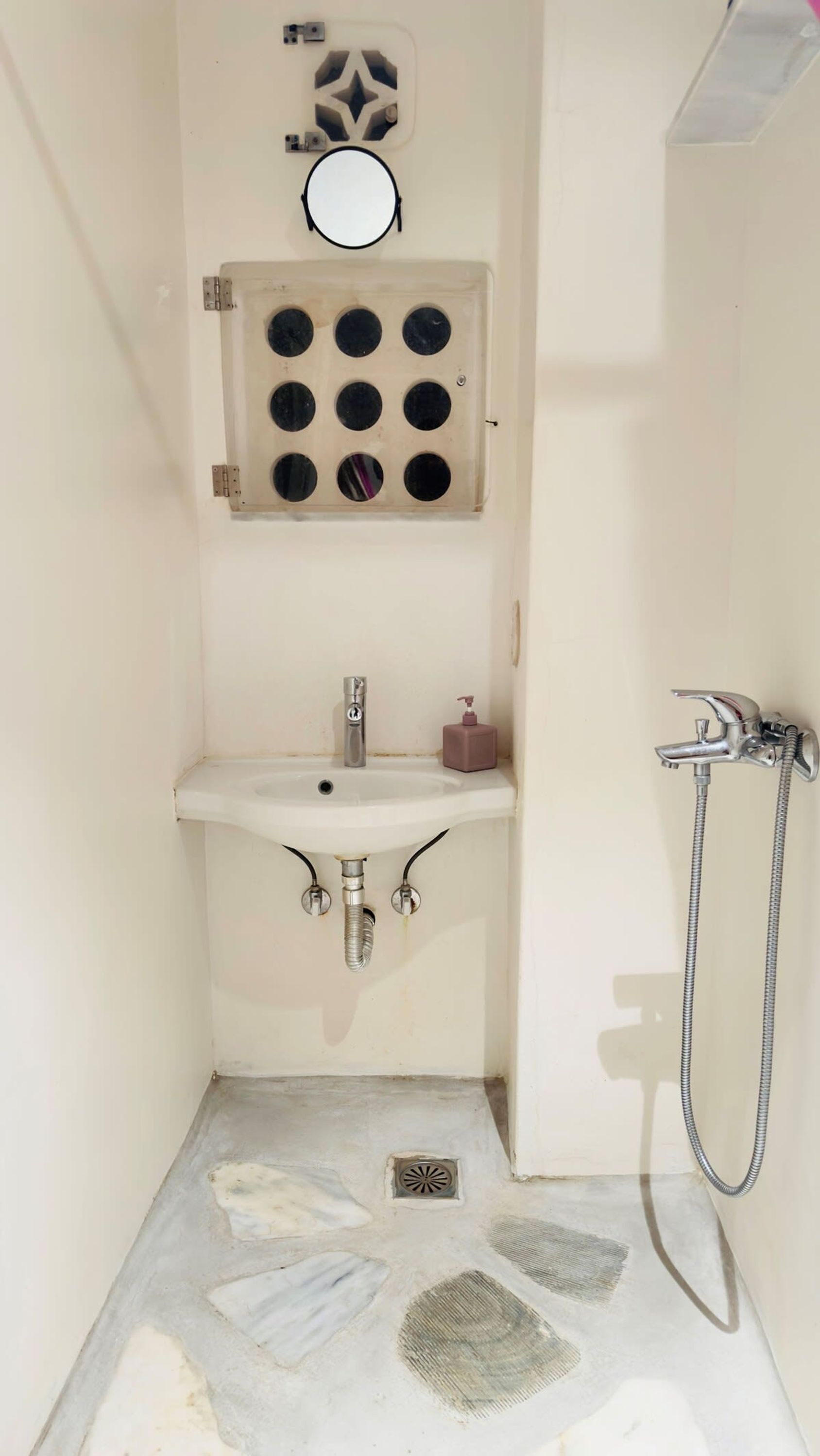 Un baño pequeño con lavamanos, espejo y ducha.