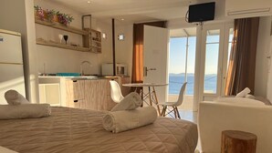 Une chambre d’hôtel avec un lit, un petit bureau, une chaise, un tabouret en bois et un téléviseur.