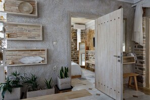 Une pièce avec un mur en pierre, une porte en bois, un lit et une petite table.