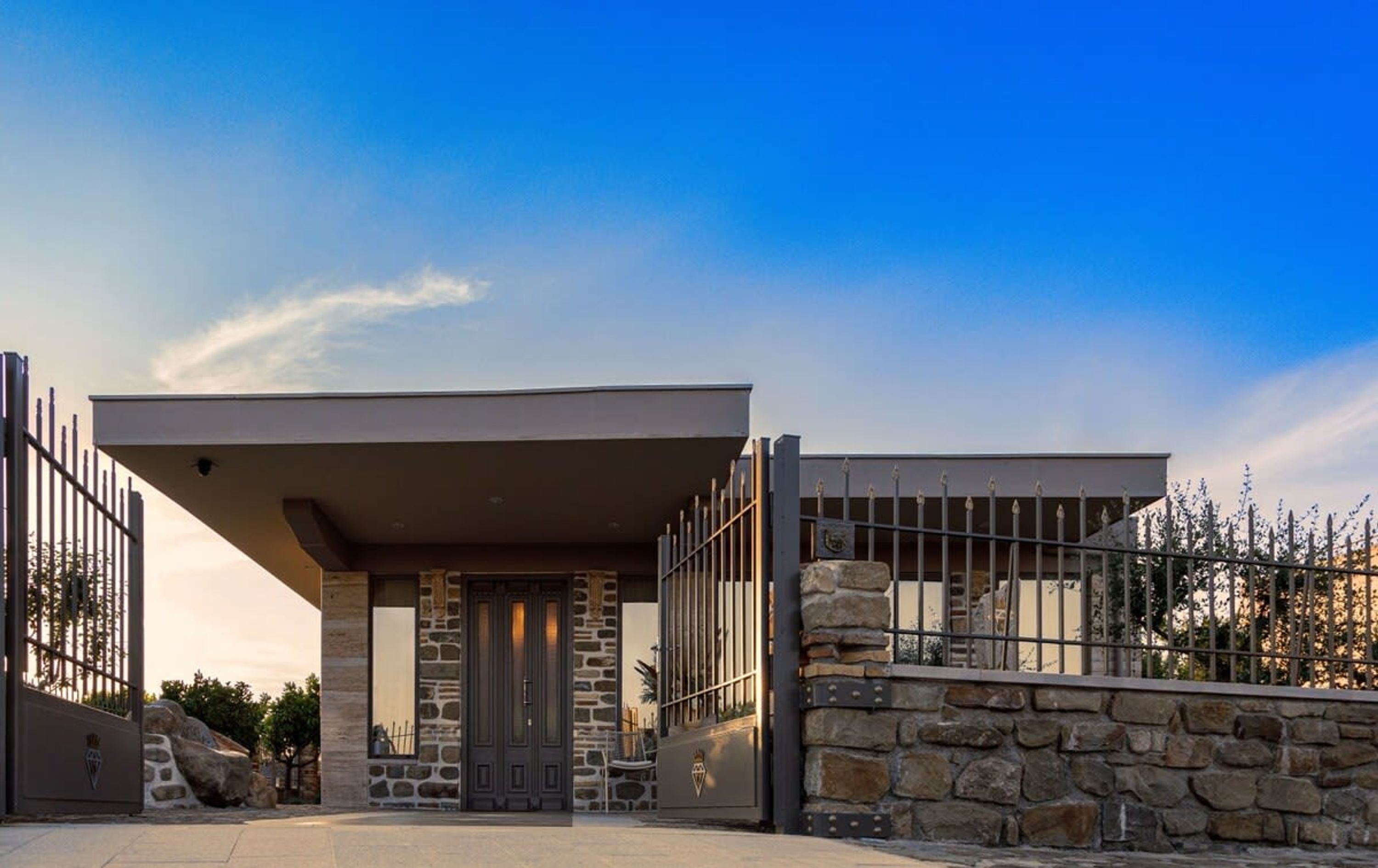 A modern building with a stone facade, a metal gate, and a clear sky.