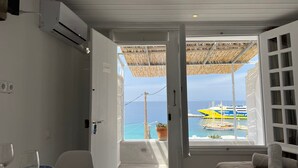 Ein Zimmer mit Balkon und Blick auf eine Marina, ausgestattet mit einem Bett, einem Tisch mit Weinglas und einer Klimaanlage.