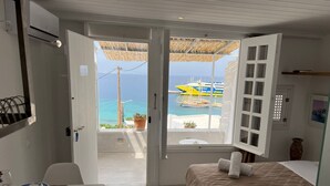 Ein Zimmer mit einem Bett, einem Tisch mit Tellern und Gläsern sowie Blick auf Boote auf dem Wasser.