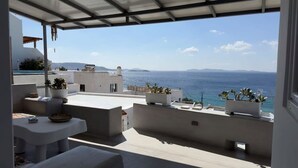 A terrace with a view of the sea, potted plants, and a table. - Mykonos Noir Nest - Sea View Escape (Mykonos)