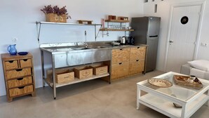 A compact kitchen with a stainless steel sink, wooden cabinets, and a refrigerator. - Mykonos Noir Nest - Sea View Escape (Mykonos)