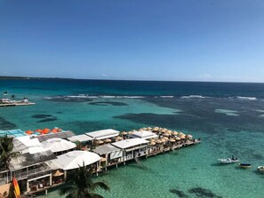 An overwater bungalows with clear turquoise water, a pier, and a small boat.