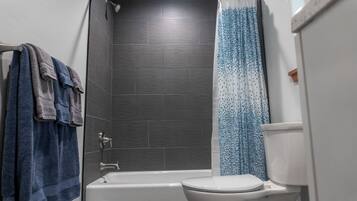 Une salle de bain équipée d’une baignoire, de toilettes et d’un rideau de douche.