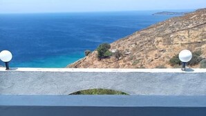 Un balcón con vista al mar y una ladera rocosa.