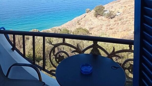 Un balcón con vista al mar y una ladera rocosa.