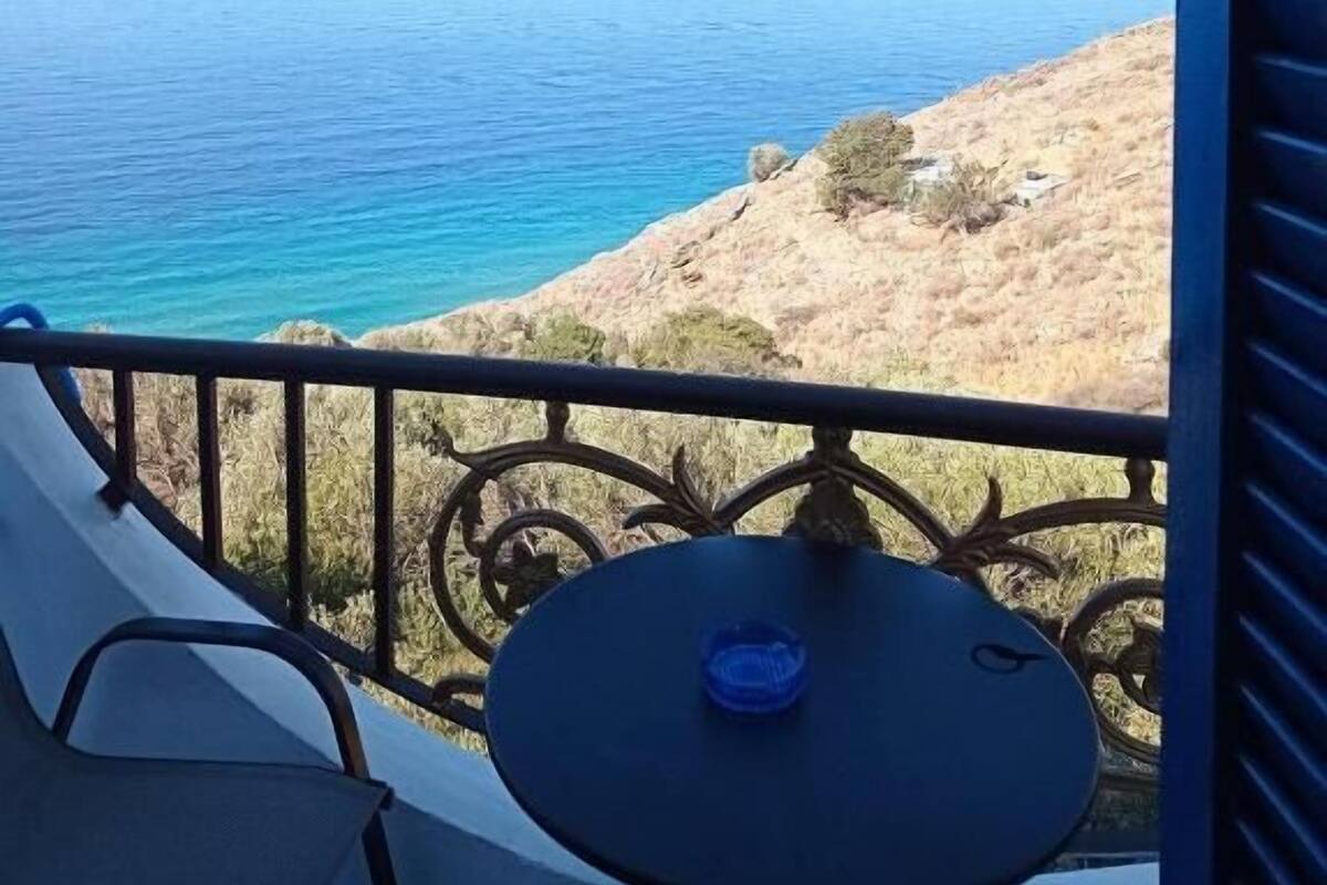 A balcony with a view of the sea and a rocky hillside.