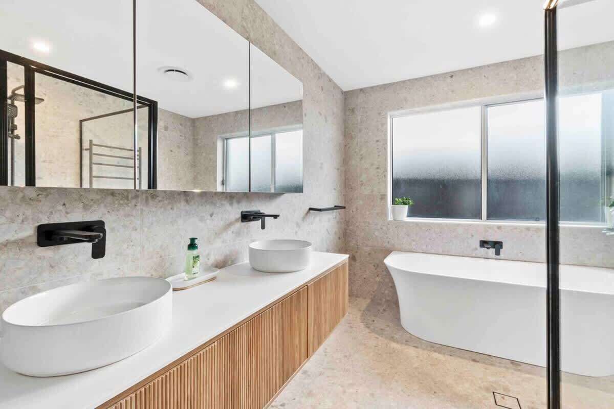 A modern bathroom with a large freestanding bathtub, a double sink vanity, and a large mirror.