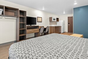 A modern hotel room with a large bed, a desk with a chair, a television, a microwave, and a refrigerator. - Woodspring Suites Palmdale - Lancaster (Palmdale)