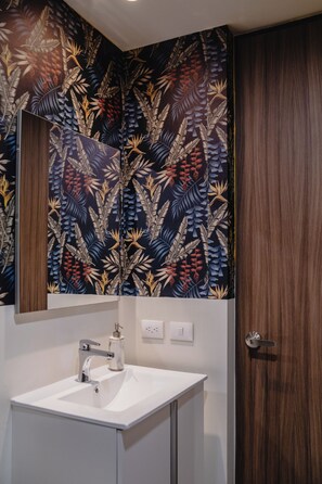 A bathroom with a white sink, a mirror, and a wooden door.