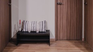 Un pasillo con un banco de madera, cuadros en la pared y una gran puerta de madera.