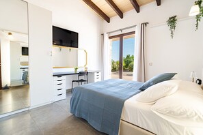 Ein Schlafzimmer mit Bett, Schreibtisch und Blick ins Freie.