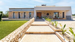 A modern two-story house with a stone facade, a paved driveway, and a well-maintained lawn. - VILLA NIMAF - SA PLANERA (Marratxi)
