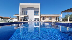 A modern hotel with a large swimming pool, outdoor seating, and a stone facade. - VILLA NIMAF - SA PLANERA (Marratxi)