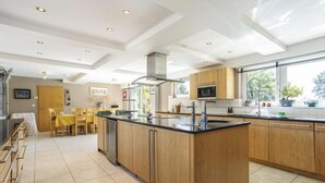 Una cocina moderna con una isla central, armarios de madera, un microondas y un amplio ventanal que proporciona luz natural.