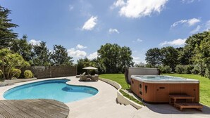 Una piscina con jacuzzi, sillas de descanso y una terraza de madera.