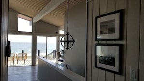 Une pièce spacieuse avec vue sur l’océan, un plafond en bois et un balcon équipé de chaises.