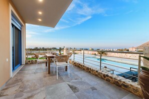 A balcony with a pool, outdoor seating, and a view of the city.