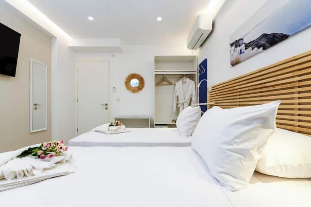 Ein Hotelzimmer mit einem Bett, einem Kleiderschrank, einem Spiegel, einem an der Wand montierten Fernseher und einem Bild.