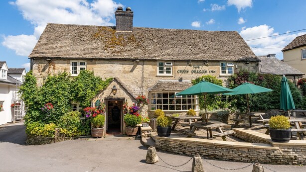 A traditional stone building with a sign reading "The Green Dragon Inn."