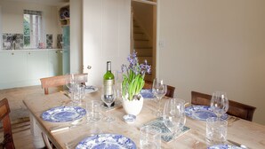 A dining table set with blue and white plates, wine glasses, and a bottle of wine.