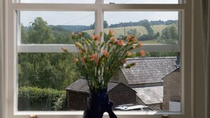 A window with a view of a rural landscape, including fields and a wooden building.