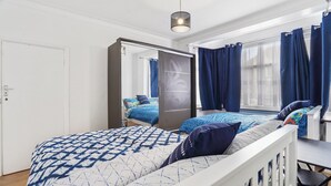 Een moderne slaapkamer met een bed, een kledingkast, een bureau en een raam met gordijnen.