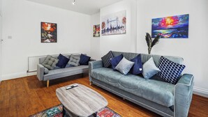 Een moderne woonkamer met twee banken, een salontafel en kunstwerken aan de wanden.